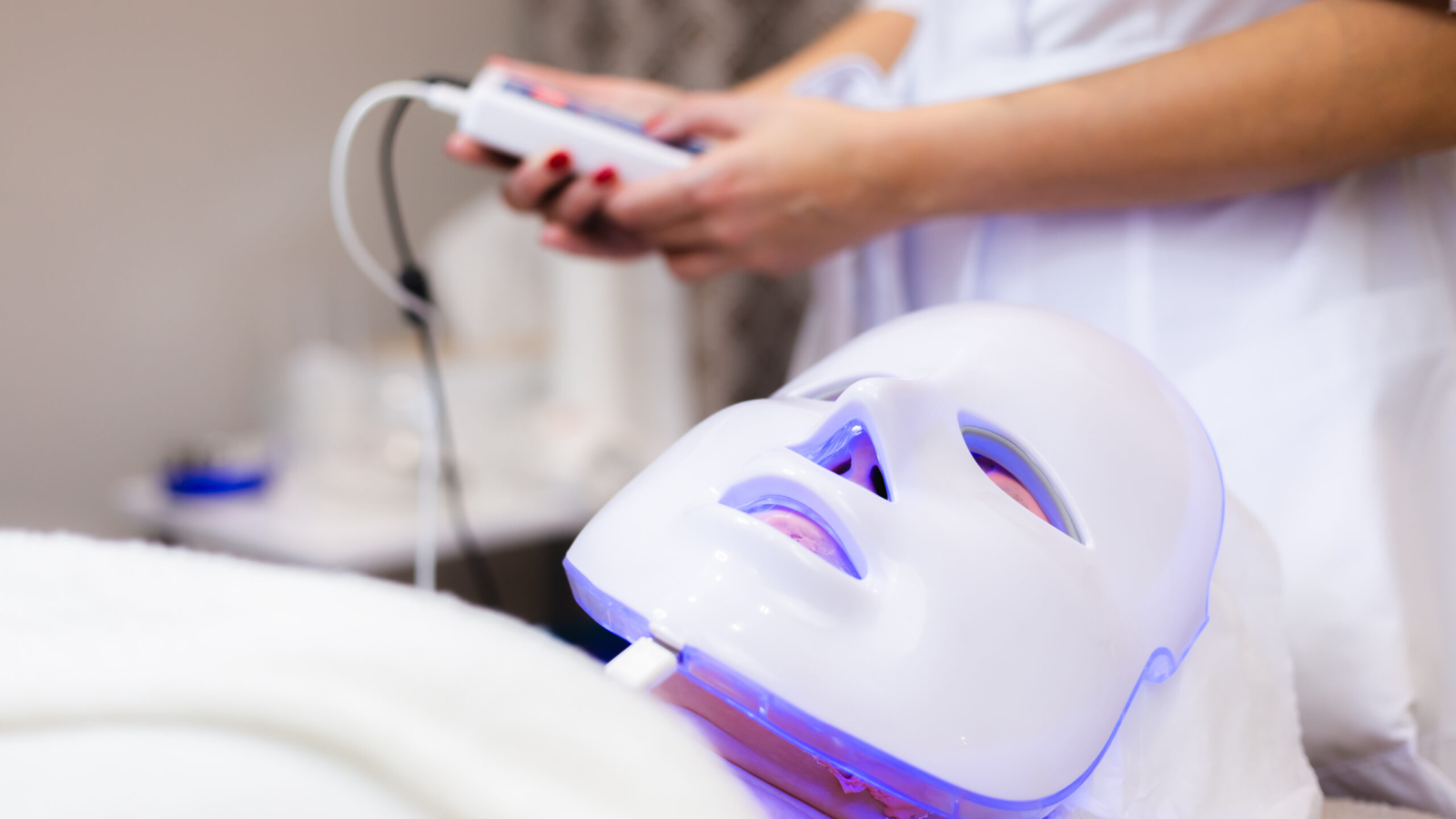 The client lies in the salon on the cosmetology table with a white mask on her face